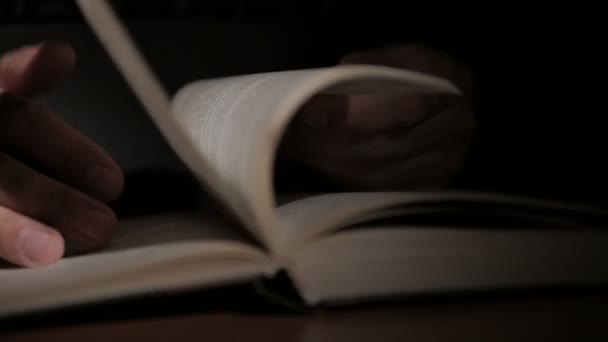 Close-up mans ruka drží otevřenou knihu, obrací stránky s prsty