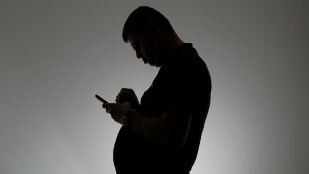 The silhouette of a man with a curved spine. A stooping man with a mobile phone in his hands. — Stock Footage The silhouette of a man with a curved spine. A stooping man with a mobile phone in his hands. Royalty Free Stock Video