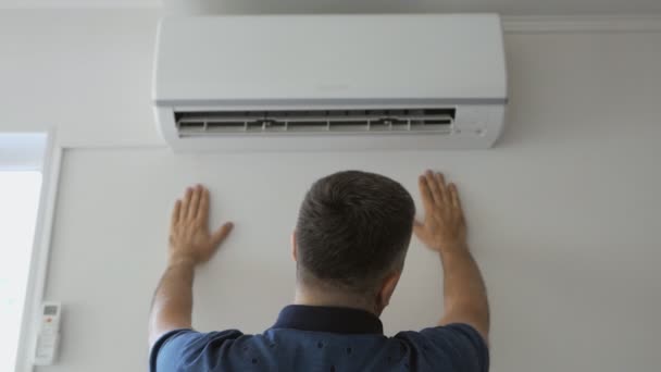 A man dripping with sweat cools under a stream of cold air standing next to a working air conditioner. — Stock Footage A man dripping with sweat cools under a stream of cold air standing next to a working air conditioner. Stock Video