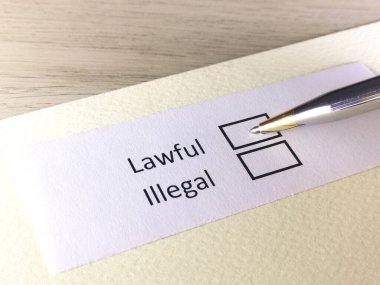 Bir kişi bir kağıt parçasındaki soruya cevap veriyor. Bu kişi yasal ya da yasa dışı olduğunu düşünüyor..