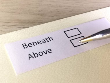 Bir kişi bir kağıt parçasındaki soruya cevap veriyor. Kişi yukarıda ya da altında olmayı düşünüyor..