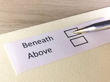 Bir kişi bir kağıt parçasındaki soruya cevap veriyor. Kişi yukarıda ya da altında olmayı düşünüyor..