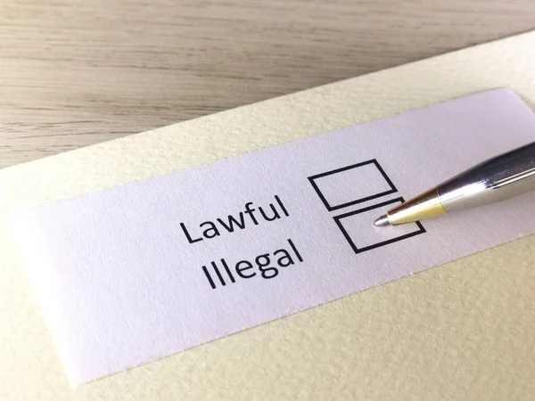 Bir kişi bir kağıt parçasındaki soruya cevap veriyor. Bu kişi yasal ya da yasa dışı olduğunu düşünüyor..