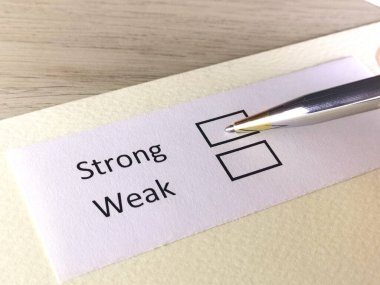 Bir kişi bir kağıt parçasındaki soruya cevap veriyor. Kişi güçlü ya da zayıf olmayı düşünüyor..