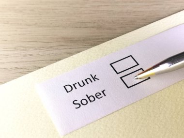 Bir kişi bir kağıt parçasındaki soruya cevap veriyor. Sarhoş ya da ayık olmayı düşünüyor..