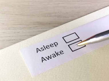 Bir kişi bir kağıt parçasındaki soruya cevap veriyor. İnsan uyumayı ya da uyanık olmayı düşünüyor..