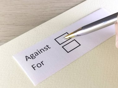 Bir kişi bir kağıt parçasındaki soruya cevap veriyor. Bu kişi karşı ya da lehine karar vermeyi düşünüyor..