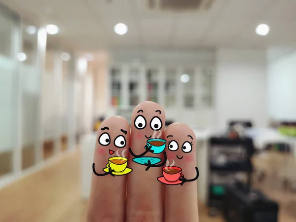 Three fingers are decorated as three person. They are having hot coffee in office.