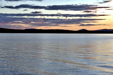 akşam gökyüzü göl güneş tarafından aydınlatılmış bulutlar siluetleri üzerinde
