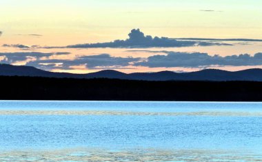 akşam gökyüzü göl güneş tarafından aydınlatılmış bulutlar siluetleri üzerinde