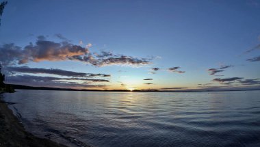 göle siluetleri güneş tarafından aydınlatılmış bulutların üzerinde akşam gökyüzü güneş ufukta ayarlar.
