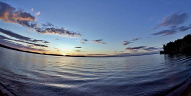 göle siluetleri güneş tarafından aydınlatılmış bulutların üzerinde akşam gökyüzü güneş ufukta ayarlar.