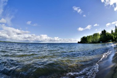 Cumulonimbus beyaz bulutların göl temiz su üzerinde kayalık altında görebilirsiniz