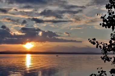 göl, gölün kıyısında orman kaplı güneş tarafından aydınlatılmış bulutlar siluetleri üzerinde akşam gökyüzü
