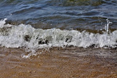 yaklaşmakta olan dalga sprey bir sürü verir, Sprey Güneş tarafından aydınlatılmış