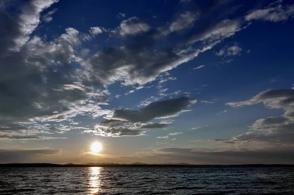 傍晚的天空笼罩着湖面 阳光照耀着云彩的剪影 — 图库照片