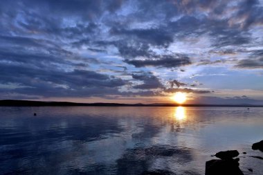 akşam gökyüzü göl güneş tarafından aydınlatılmış bulutlar siluetleri üzerinde
