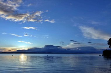akşam gökyüzü göl güneş tarafından aydınlatılmış bulutlar siluetleri üzerinde