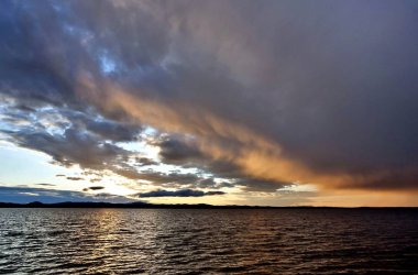 karanlık gece göl ve turuncu güneşli bulutlar