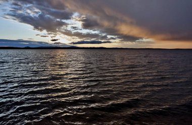 karanlık gece göl ve turuncu güneşli bulutlar