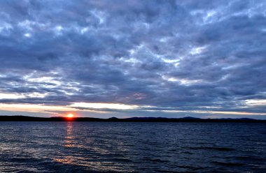akşam gökyüzü göl güneş tarafından aydınlatılmış bulutlar siluetleri üzerinde