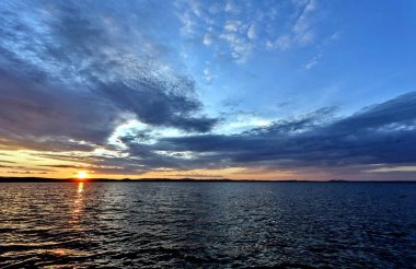 akşam gökyüzü göl güneş tarafından aydınlatılmış bulutlar siluetleri üzerinde