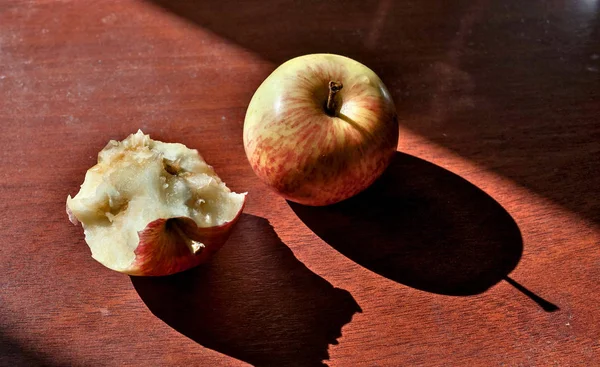 Halb Verzehrt Und Ganze Äpfel Auf Dem Tisch Liegend Erleuchtet — Stockfoto