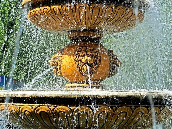 City fountain with flying splashes illuminated by the bright sun — Stock Photo, Image