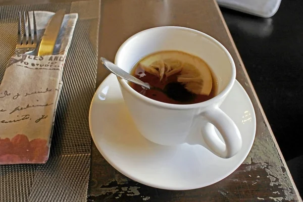 Té en una taza con una cucharadita y limón —  Fotos de Stock