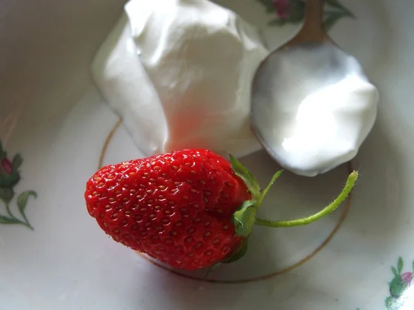 Велика стигла полунична ягода на тарілці зі сметаною, макро — стокове фото