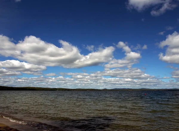 Nuages blancs dans le ciel bleu sur le lac tôt le matin — Photo