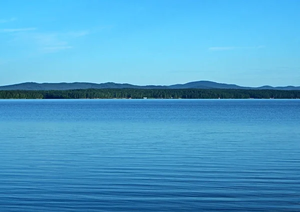 Vista de la orilla opuesta del tranquilo lago de la mañana —  Fotos de Stock