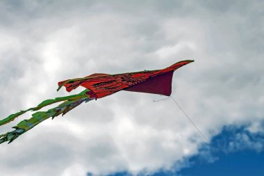 kırmızı bir kuş şeklinde uçurtma bulutlar ile mavi gökyüzünde süzülür