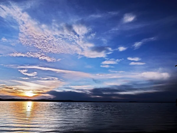 Sol naranja en el cielo azul del atardecer con nubes plumosas sobre el lago, Urales del sur — Foto de Stock