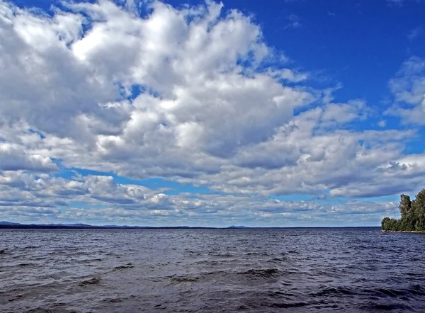 Fehér felhők a kék ég alatt a tó a kora reggeli órákban — Stock Fotó