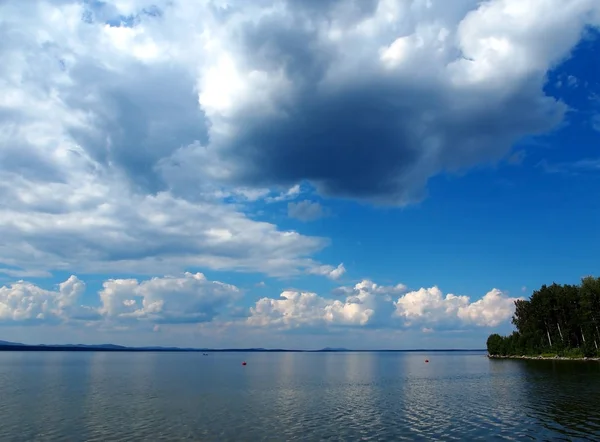 Dunkelblauer Himmel mit weißen Cumulonimbus-Wolken über dem Morgensee — Stockfoto