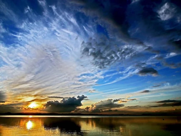 Orangefarbene Sonne am blauen Sonnenuntergangshimmel mit fedrigen, dramatischen Wolken über dem See, südliches Ural — Stockfoto