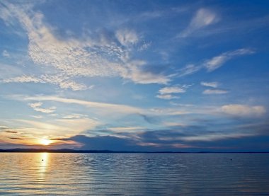 göl üzerinde tüylü bulutlar ile mavi günbatımı gökyüzünde turuncu güneş, güney Urallar