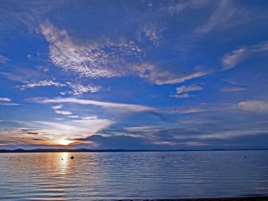 göl üzerinde tüylü bulutlar ile mavi günbatımı gökyüzünde turuncu güneş, güney Urallar