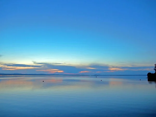 Cielo blu tramonto sul lago con nuvole fumose luce sopra l'orizzonte — Foto Stock