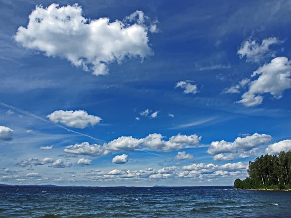 Koyu mavi gökyüzü ile beyaz kümülonimbus bulutları sabah gölünün üzerinde — Stok fotoğraf