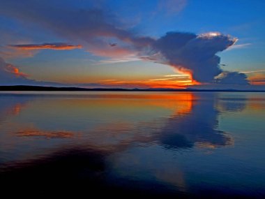 göl üzerinde tüylü bulutlar ile mavi günbatımı gökyüzünde turuncu güneş, güney Urallar