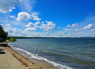 Koyu mavi gökyüzü ile beyaz kümülonimbus bulutları sabah gölünün üzerinde