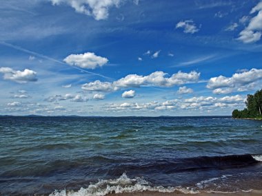 Koyu mavi gökyüzü ile beyaz kümülonimbus bulutları sabah gölünün üzerinde