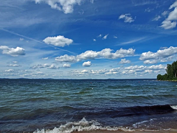 Dark blue sky with white cumulonimbus clouds over morning lake — Stock Photo, Image