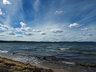 Koyu mavi gökyüzü ile beyaz kümülonimbus bulutları sabah gölünün üzerinde