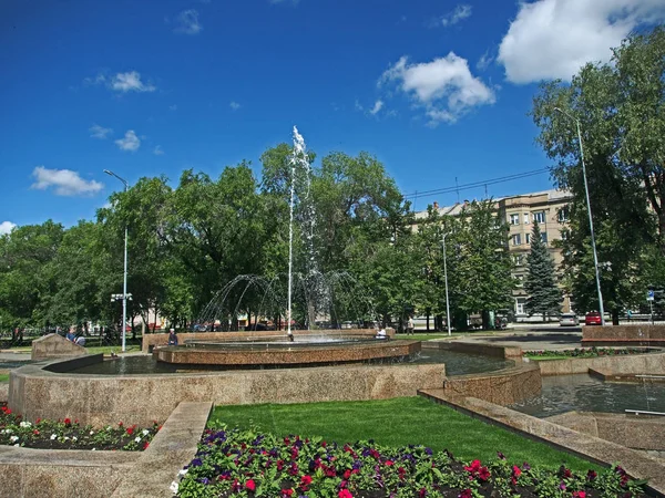 Fuente de trabajo en la plaza de la ciudad en un día caluroso contra el cielo azul, gotas de agua volando —  Fotos de Stock