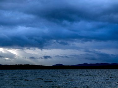 Bir yaz akşamı gölün üzerindeki karanlık bulutlar, kasvetli bulutlar, uzaktaki karşı kıyılar, Uvildy Gölü, Güney Urallar