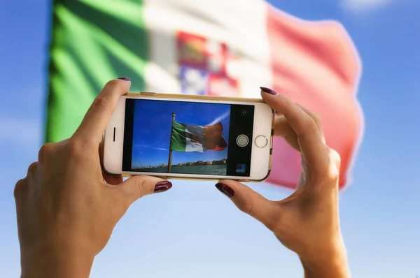 Student travels around Venice on a vaparetto and photographs the Italian flag on her smartphone. Travel concept. Mixed media