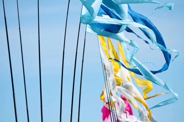 Sallanan bir blu-mavi, sarı-beyaz ve pembe gül uzun triungular üzerinde bir arka plan parlak blu sky closeup bayraklar